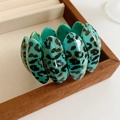 Close-up of wide turquoise leopard print resin bracelet with polished oval tiles - Blue