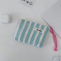 Close-up of blue striped canvas pouch with pink woven zipper pull on a clean white desk - Drawstring Pouch