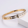 Dettaglio ravvicinato di un bracciale placcato oro con numeri romani e pavé di pietre - Oro