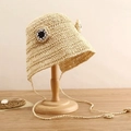 Dettaglio del cappello di paglia a rana fatto a mano con occhi decorativi e lacci lunghi - Beige