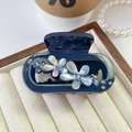 Detail shot of navy blue acetate flower hair claw with rhinestones in a jewelry box - Blue
