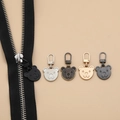 Detail of five bear-shaped metal zipper pulls in multiple metallic finishes on black zippers - Bear Shape - 5 Mixed Colors
