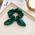 Dark green metallic crinkle fabric bow hair scrunchie on white textured tray - Glossy Green Rabbit Ears