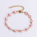 Detailansicht der rosa-weißen Evil Eye Emaille-Anhänger an einem vergoldeten Armband - Rosa
