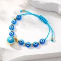 Vue détaillée du bracelet bohème fait main avec perles œil bleu et perles dorées fines - Bleu transparent