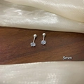 Nahaufnahme von 5mm hellblauem Zirkon Ohrstecker mit Schraubverschluss auf dunklem Holz - Großer Stil / Silber Einzelner Zirkon