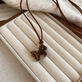 Dettaglio macro di una collana con ciondolo a cavallo a dondolo su una scatola di velluto - Cavallo a Dondolo Effetto Occhio di Tigre Ambra (HN10851)