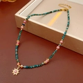 Dettaglio della collana con ciondolo a sole, perle verdi e pietra rosa su astuccio - Collana-Oro-Blu-Rosa