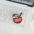 Detailed view of a cute cartoon cat in a red bowl embroidery patch on a laptop keyboard - Cat in Bowl
