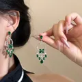 Close-up of emerald green tassel earrings featuring a silver base and sparkling gemstones - 7# 925 Sterling Silver Earring Post - Silver & Green
