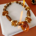 Detailed view of amber resin beaded necklace with teardrop pendant on velvet stand - Necklace-Coffee Water Drop