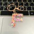 Resin initial F keychain with colorful heart glitter and gold metal keyring on keyboard - Letter F