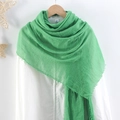 Solid green pleated cotton linen scarf with frayed edges hanging on a wooden hanger - Green