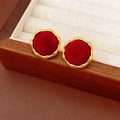 Gros plan de boucles d'oreilles en velours rouge avec cadres dorés dans un écrin en bois - Rond / Rouge