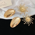 Dettaglio di spille a girasole dorate e orecchini ovali su tessuto elegante - Set da 4 pezzi / Oro