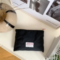 Detail of black pleated nylon makeup bag with pink zipper on a minimalist white desk - Black (Horizontal)