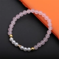 Bracciale di perle e cristalli rosa con ciondolo a stella dorata su sfondo nero - Quarzo Rosa Farfalla