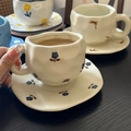 Detail of a ceramic coffee cup and saucer set with hand-painted blue flowers and brown birds - Matte Little Orchid