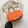 Orange quilted chain shoulder bag with gold hardware held over a beige blazer - Orange