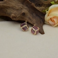 Gros plan de pendentifs cubes en cristal rose avec bordure dorée sur du bois - Rose Foncé