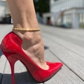 Elegante gouden Cubaanse schakel enkelband set met rode spitse hakken op een houten terras - Enkele Gouden Enkelband - Modestijl