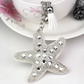 Close-up of starfish keychain with glass crystals, white tassel and small silver bell - White