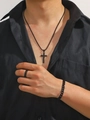 Close-up of black metal cross pendant necklace, patterned ring, and chain bracelet set - Black