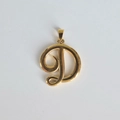 Vue macro d'un pendentif en acier inoxydable doré 18K avec la lettre D en cursive - Pendentif uniquement / Pendentif D