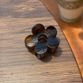 Détail de la pince à cheveux fleur ambre à six pétales sur une surface en bois - 5cm / Écaille Claire Brillante