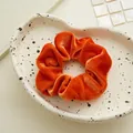 Dettaglio di un elastico per capelli in velluto arancione con texture soffice e lucida - Velluto Arancione