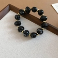 Detail of beaded bracelet featuring black marbled acrylic beads and gold metal spacers - Bracelet / Black