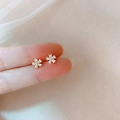 Delicate gold flower stud earrings with sparkling zircon petals held on fingers - Zircon Five-Petal Flower Style (56#银针-锆石花朵)