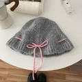 Knitted bucket hat in grey wool with pink bow tie ribbon detail on a white table - Hat / Gray