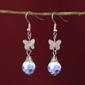 Silver butterfly earrings with blue floral ceramic beads hanging on a branch - E4 Blue and White Butterfly Earrings (Large Flower)