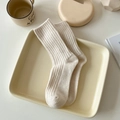 Calze beige in misto lana a coste verticali esposte su un vassoio di ceramica - Taglia unica / Crema