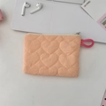 Detalle del monedero naranja con acolchado de corazones y cremallera en la mesa - Acolchado de Corazón Naranja Monedero