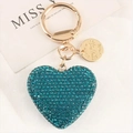 Detailed view of heart-shaped keychain with teal rhinestones and a gold metal logo tag - Blue Heart