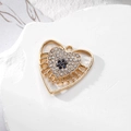 Primer plano del colgante corazón dorado con diamantes de imitación y gema azul - Corazón Hueco Dorado Ojo Azul