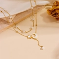 Detailed close-up of double-layered gold necklace with pearls and celestial star moon charms - Double Layer Pearl Star Moon Tassel Necklace / Gold