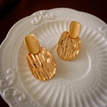 Close-up of gold geometric earrings with fluid texture on a white ceramic tray - Gold Pleated Geometric Stud Earrings (Silver Pin)