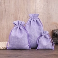 Three purple drawstring burlap pouches in various sizes displayed on a wooden surface - Purple