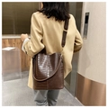Detailansicht der braunen Bucket Bag mit Krokodilmuster, breitem Riemen und Glanz - Braun