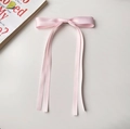 Vue détaillée du nœud en satin rose avec de longs rubans sur un fond de couleur neutre - Rose