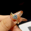Detailopname van een gouden moissanite ring met grote ronde solitair op vinger - US 7 / Goud met witte steen