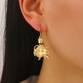 Nahaufnahme von Vintage-Goldohrringen mit Löwen- und Kronenmotiven am Modellohr - Ohrringe / Gold