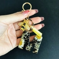 Detailed macro view of resin letter M keychain with white dried flowers and gold foil flakes - Letter M