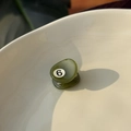 Detailed close-up of a mini green acetate hair claw with number 6 in a ceramic bowl - Emerald Green Billiard / Emerald Green/No.6