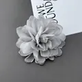 Gedetailleerd bovenaanzicht van een handgemaakte grijze stoffen chrysantspeld en haarklem - Grijs