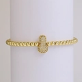 Golden beaded stretch bracelet featuring a pave zircon peanut charm on a display stand - Letter I