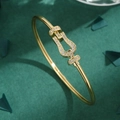 Luxurious gold horseshoe buckle bracelet with micro-pave zircons on a dark green background - Gold